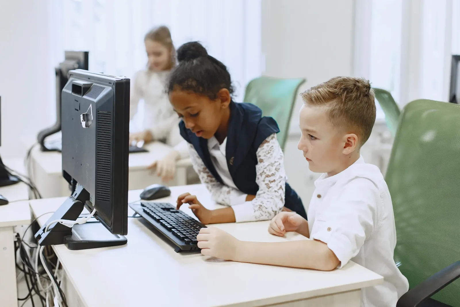 Children of varying ages working on computers together in a shared lab setting
