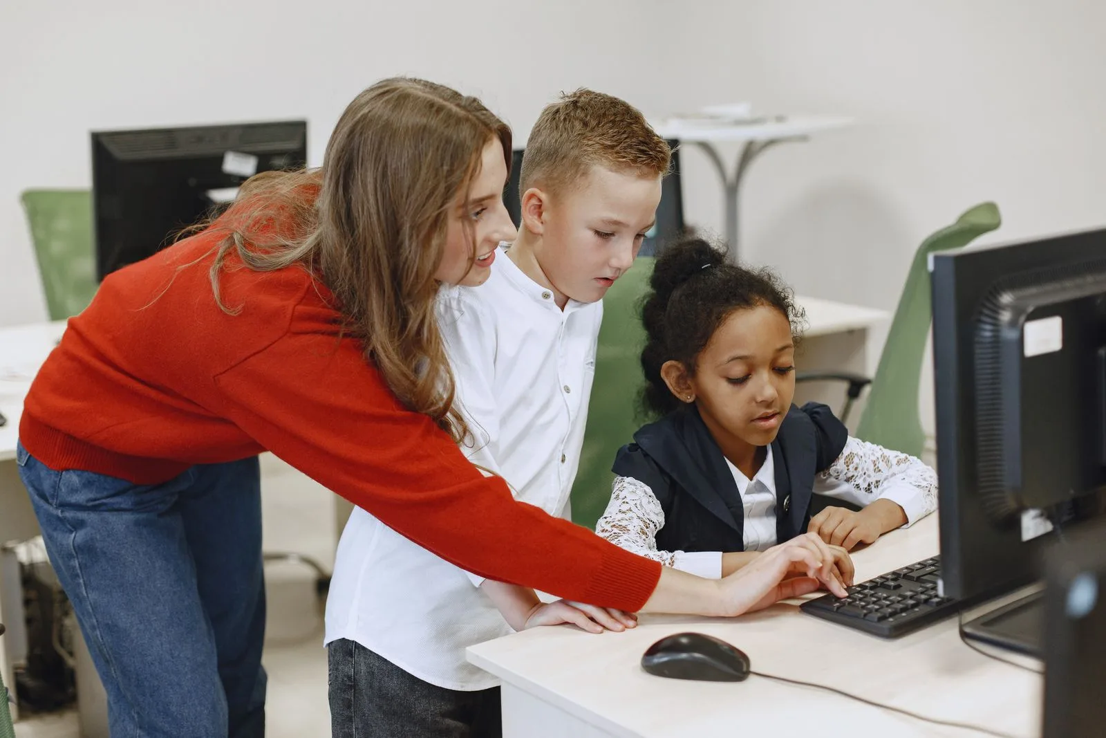 A teacher helping students work through a design activity on classroom computers