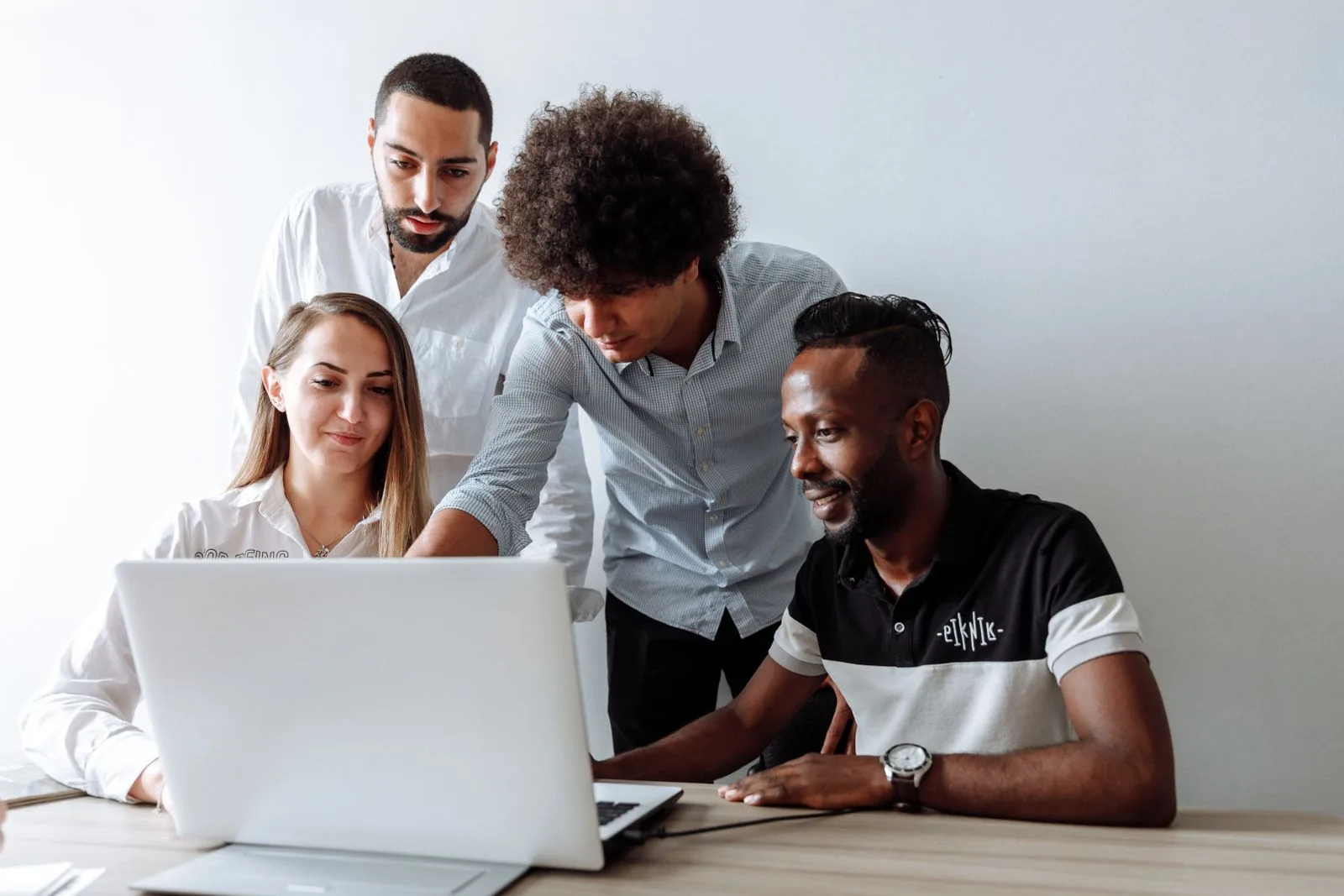 A group of people reviewing feedback together around a laptop